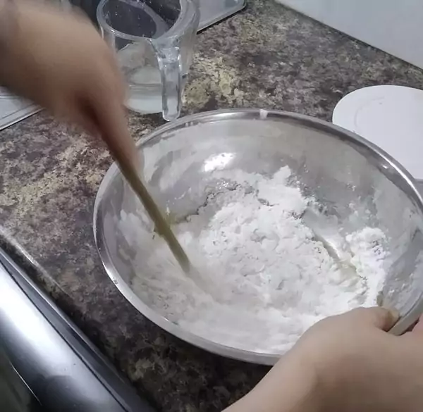 Mixing pizza dough with the wrong end of a wooden spoon makes scraping the dough off it really easy - great homemade pizza hack