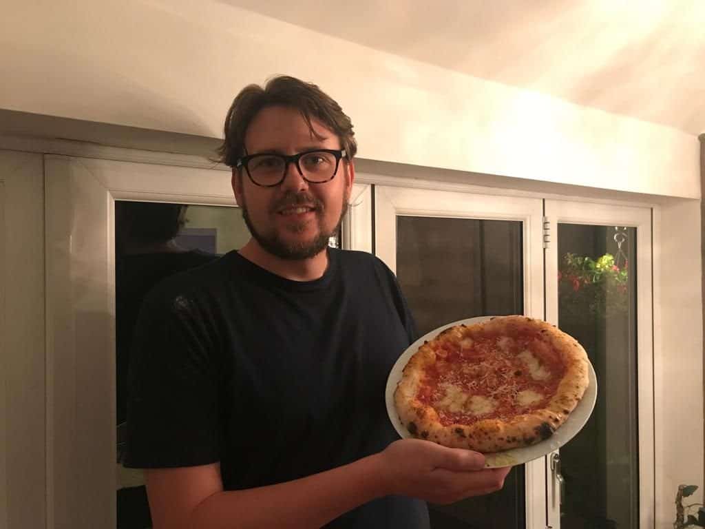 Tom Rothwell holding up Neapolitan pizza