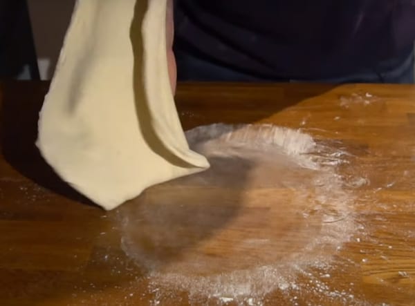 Turning the pizza dough over
