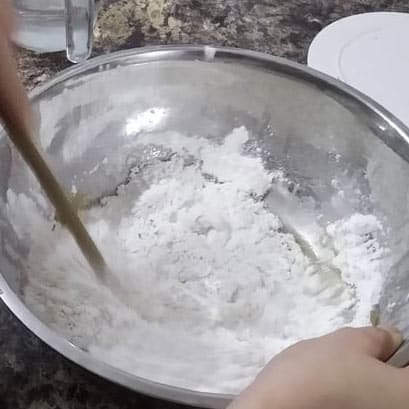 Mixing New York pizza dough with spoon