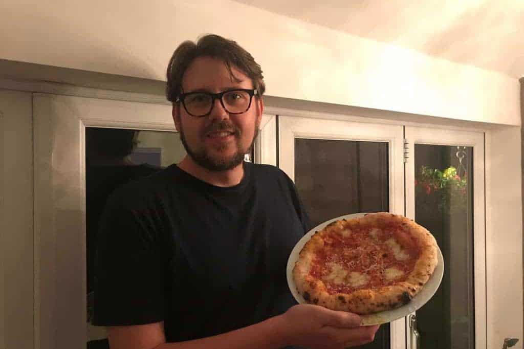 Tom from MyPizzaCorner holding up homemade pizza